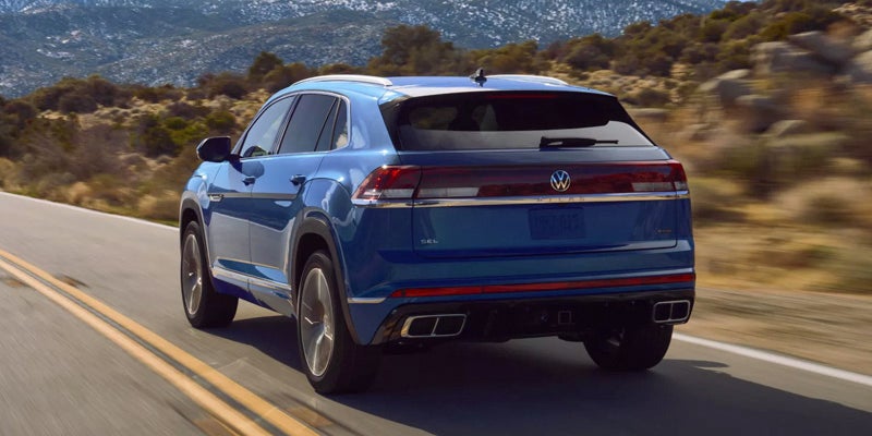 2026 Volkswagen Atlas Cross Sport rear view driving on scenic mountain road