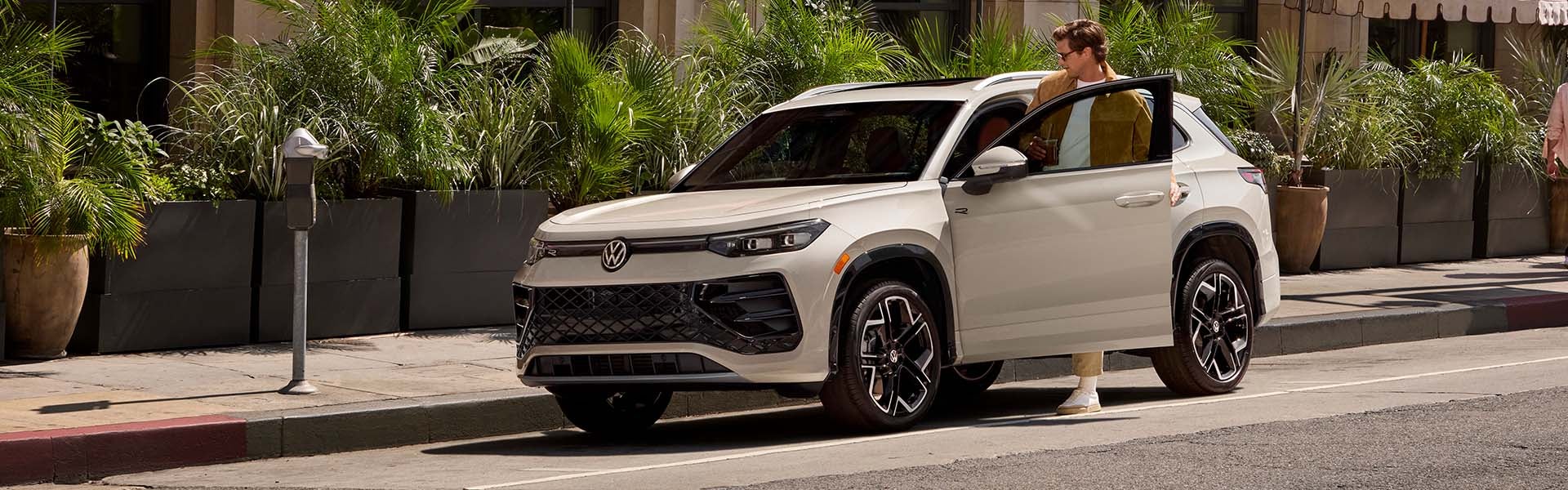 White 2026 Volkswagen Tiguan parked on a city street with driver stepping out.