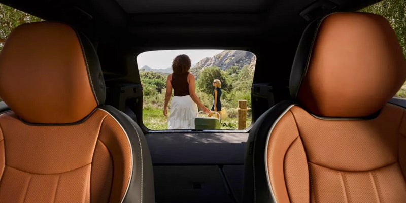 Interior view of the 2026 Volkswagen Tiguan with tan leather seats and open cargo area overlooking a scenic mountain setting.